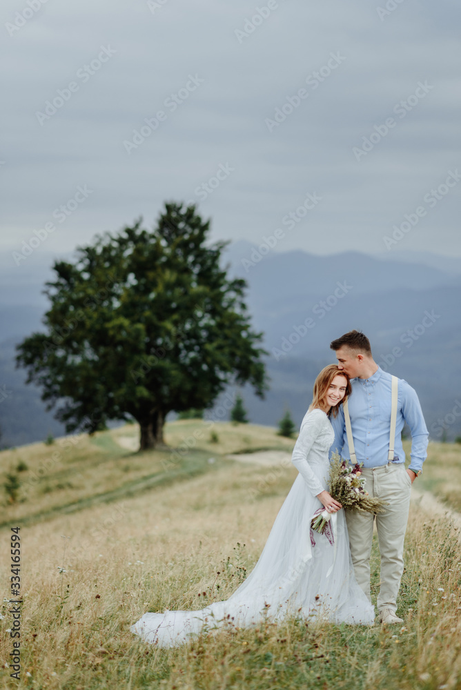 Photoshoot of the bride and groom in the mountains. Boho style wedding photo.