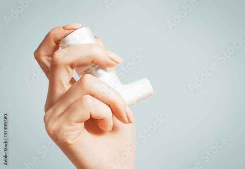 Female hand with a medical asthma inhaler, close-up. photo