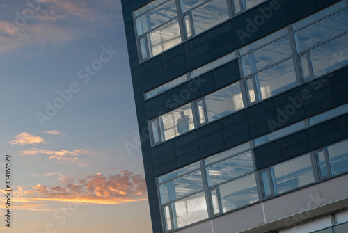 Man in window of office building on bluew sky in twilight