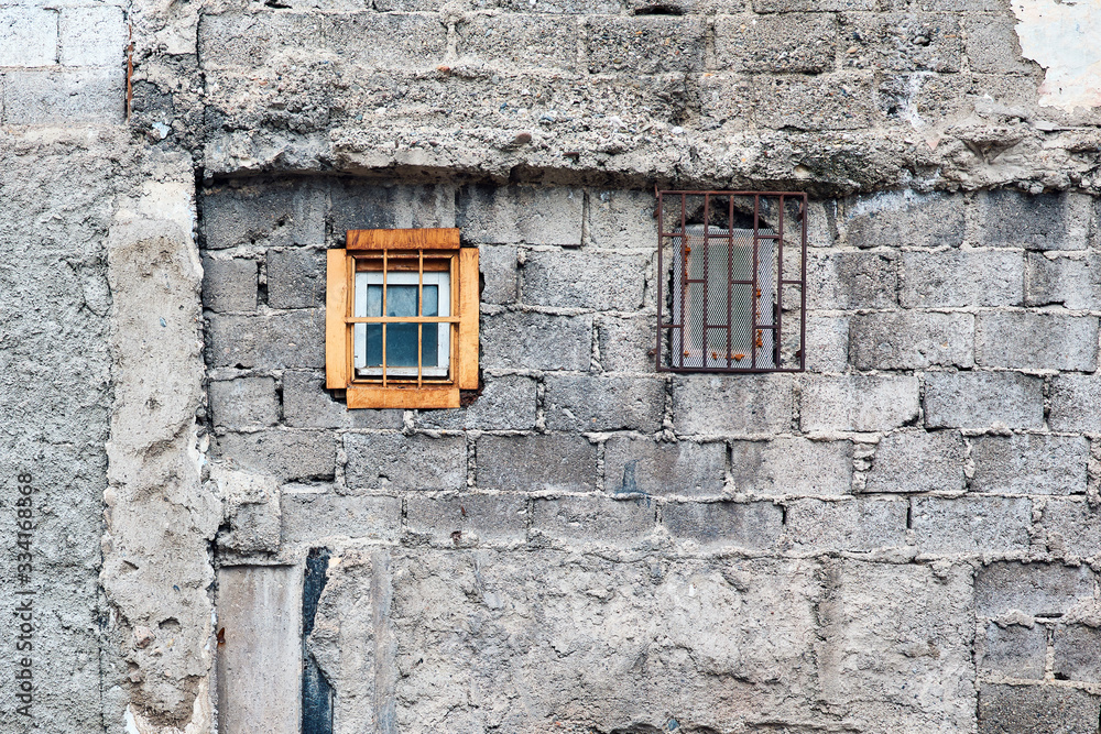 Concrete brick wall and small windows of an abandoned old building exterior. Concrete brick wall and small windows of an abandoned old building exterior.