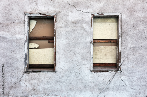 Boarded up windows and cracked peeled dirty walls of an abandoned old building photo