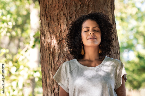 Photo Peaceful woman leaning against a tree with her eyes closed