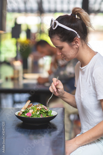 Young beautiful woman enjoying heathy salad sitting at the vegetarian restaurant. Healthy food concept