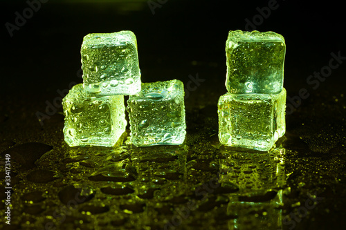 Green ice cubes on black table background. © peterkai
