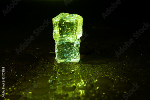 Green ice cubes on black table background.