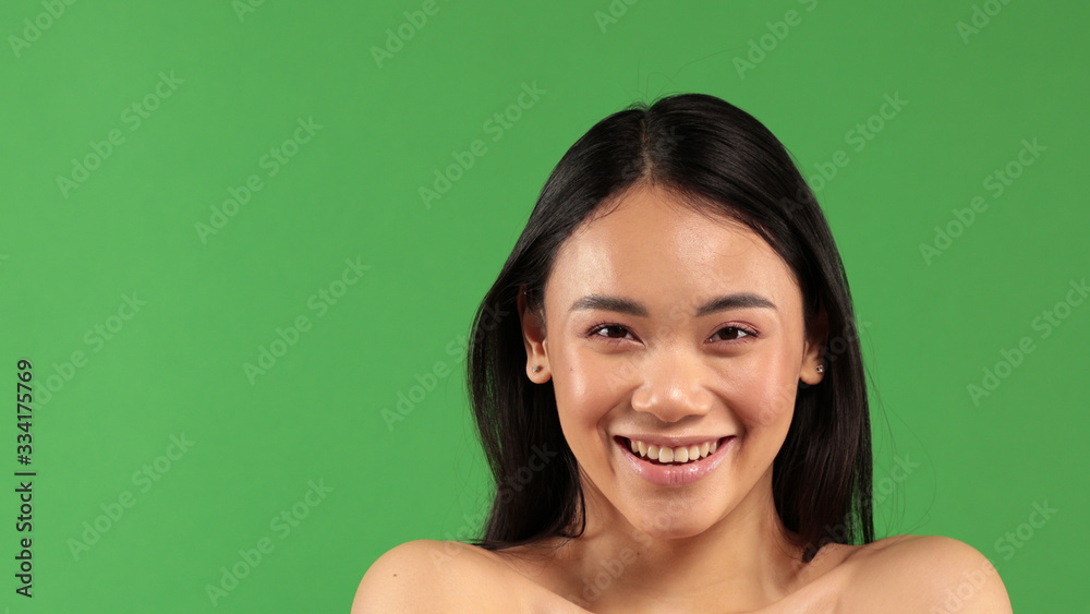 Happy smiling and looking at camera young beauty girl face on green background Happy smiling and looking at camera young beauty girl face on green background