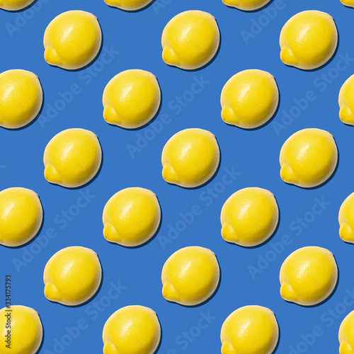 Seamless pattern of fresh lemons on blue background. Food texture