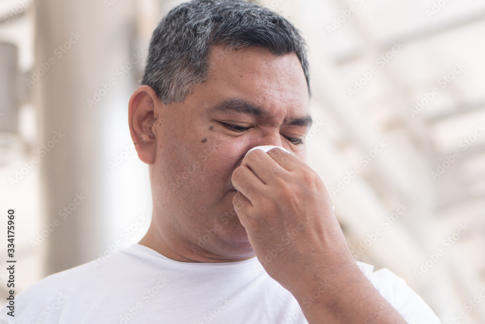 allergic sick old man wiping his runny nose and touching his face; concept of man with coronavirus covid-19 infection disease, allergy, lung inflammation, pneumonia, influenza, flu, cold, sickness allergic sick old man wiping his runny nose and touching his face; concept of man with coronavirus covid-19 infection disease, allergy, lung inflammation, pneumonia, influenza, flu, cold, sickness