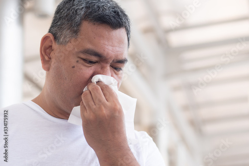 allergic sick old man wiping his runny nose and touching his face; concept of man with coronavirus covid-19 infection disease, allergy, lung inflammation, pneumonia, influenza, flu, cold, sickness