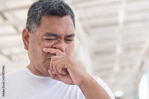 allergic sick old man wiping his runny nose and touching his face; concept of man with coronavirus covid-19 infection disease, allergy, lung inflammation, pneumonia, influenza, flu, cold, sickness