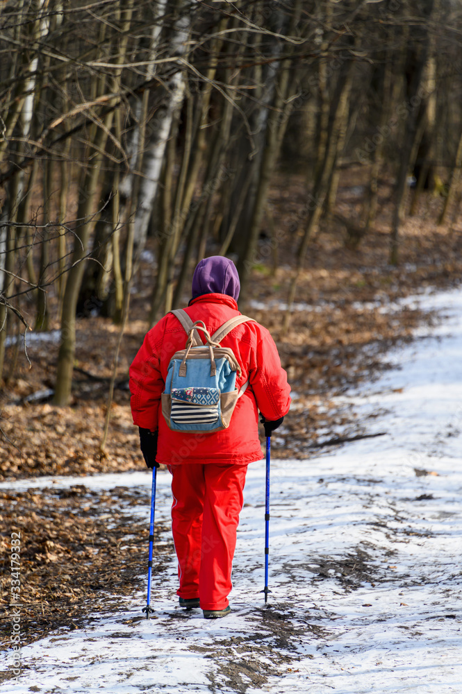 Nordic walking. A woman walking in the woods or Park in winter. Active and healthy lifestyle.