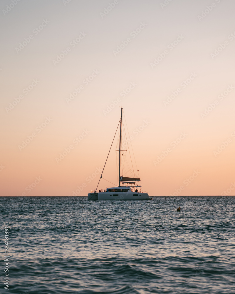 Mediterranean Sea beach at Majorca island, stunning seaside scenery of boat sailing at sunset