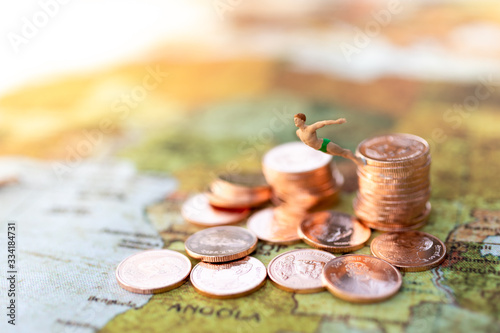 Miniature people :Traveler jump to the coins. Image use for business, travel concept