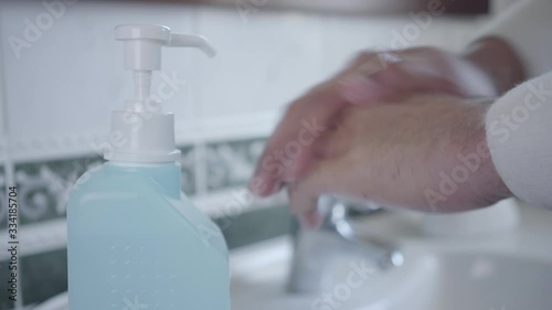 Close-up of man disinfecting hands with hand sanitizer. Male palms applying liquid in bathroom during coronavirus quarantine. Health care, medicine, Covid-19, isolation, hygiene. photo