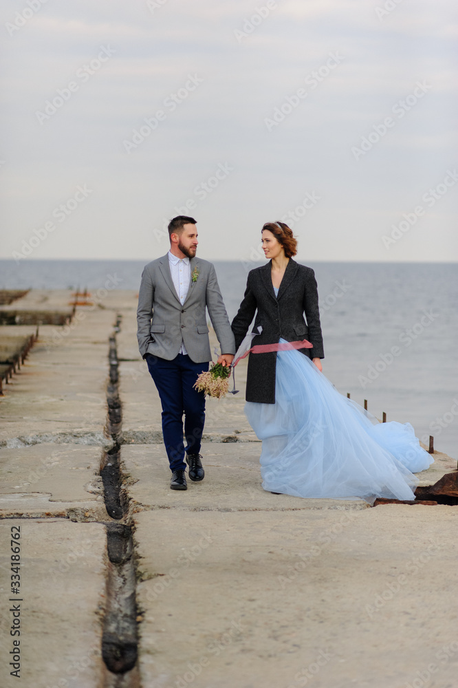 Wedding photo session of a couple on the seashore. Blue wedding dress on the bride. Wedding photo session of a couple on the seashore. Blue wedding dress on the bride.