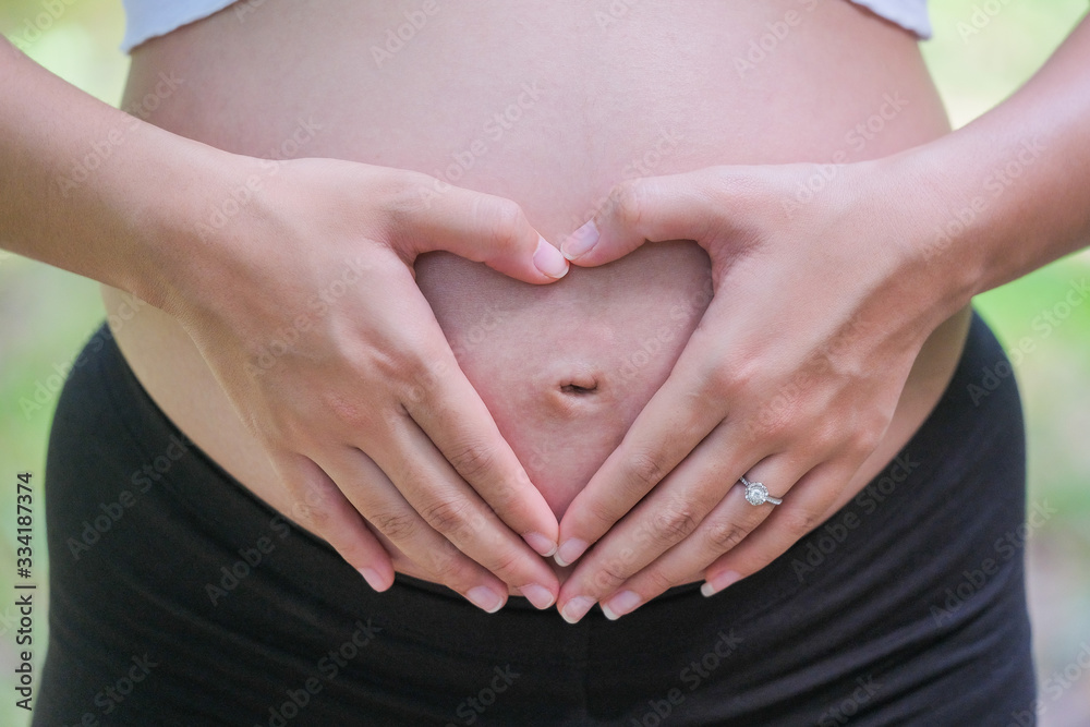 custom made wallpaper toronto digitalWoman holding her hands in a heart shape on her pregnant belly.