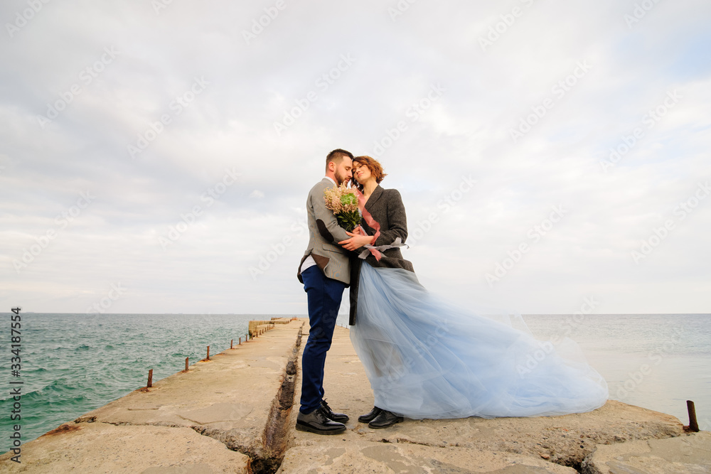 Wedding photo session of a couple on the seashore. Blue wedding dress on the bride. Wedding photo session of a couple on the seashore. Blue wedding dress on the bride.