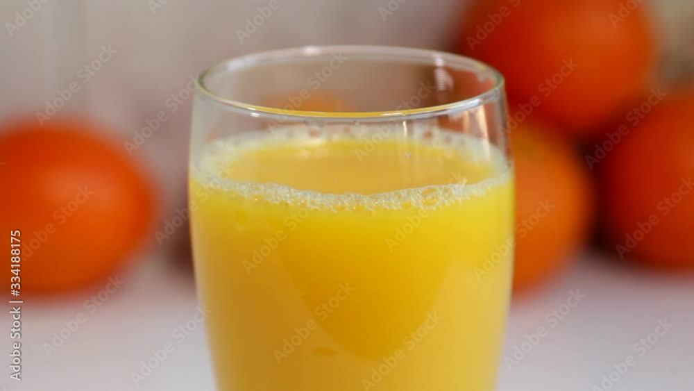 Orange juice is poured into a tall glass, on a white kitchen table with tangerines, in the kitchen. Orange juice is poured into a tall glass, on a white kitchen table with tangerines, in the kitchen.