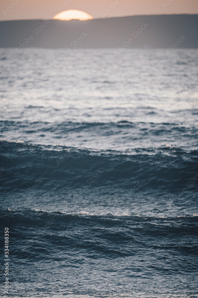 Fototapeta premium Waves at sunset with blurry sunset