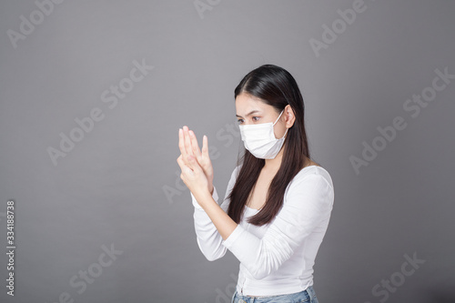 Portrait of woman with surgical mask using alcohol gel sanitizer