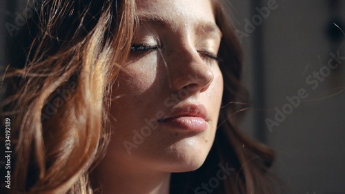 Young face woman at sunlight with curly hair fashion model with closed eyes female girl cosmetic beauty portrait confident happy cheerful enjoy relax close up