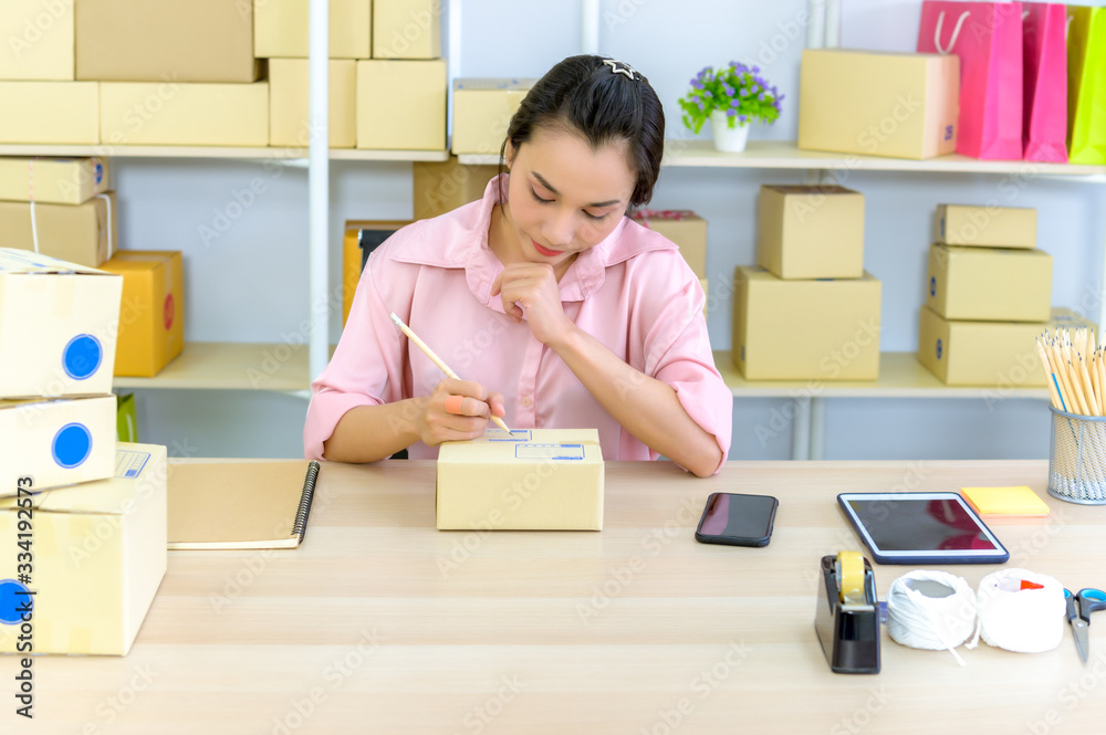 Shipping shopping online ,young start up small business owner writing address on cardboard box at workplace.small business entrepreneur SME or freelance asian woman working with box at home Shipping shopping online ,young start up small business owner writing address on cardboard box at workplace.small business entrepreneur SME or freelance asian woman working with box at home