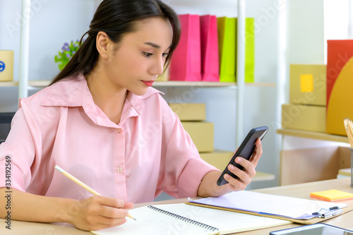Shipping shopping online  young start up small business owner writing address on cardboard box at workplace.small business entrepreneur SME or freelance asian woman working with box at home