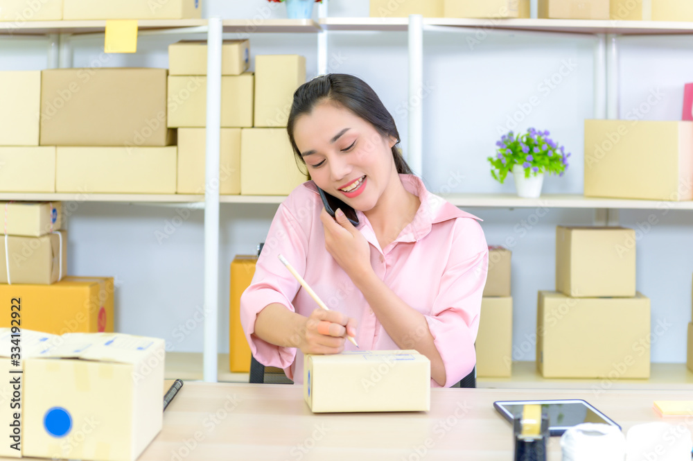 Young beautiful happy asian business woman owner of SME online using laptop receive order from customer with parcel box packaging at her startup home office, online business seller and delivery Young beautiful happy asian business woman owner of SME online using laptop receive order from customer with parcel box packaging at her startup home office, online business seller and delivery