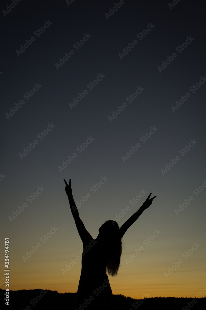 high school senior girl silhouette showing peace signs with hands in front of sunset