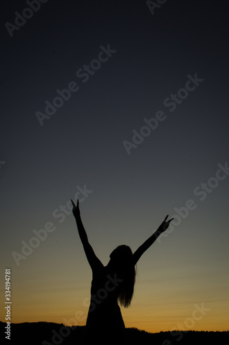 high school senior girl silhouette showing peace signs with hands in front of sunset