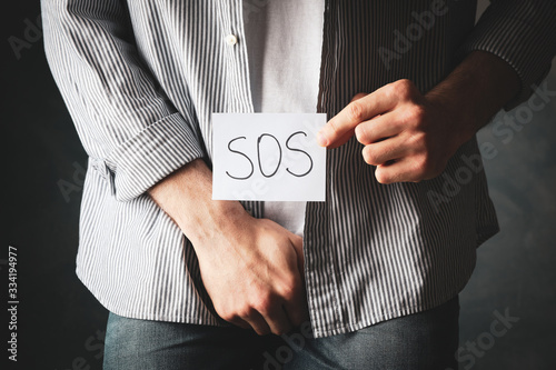 Εκτύπωση καμβά Man holds his crotch and inscription Sos on blue background, close up