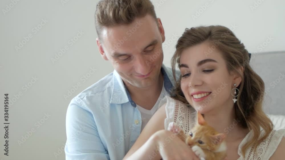 The girl and the guy are playing with the kitten and are happy The girl and the guy are playing with the kitten and are happy