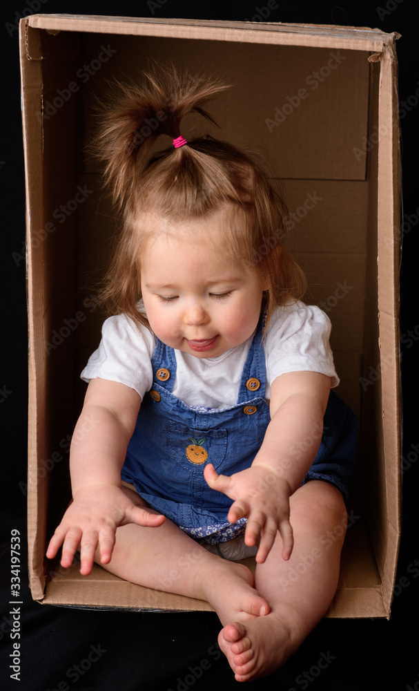 Little cute, beautiful girl sits in a box. Little cute, beautiful girl sits in a box.