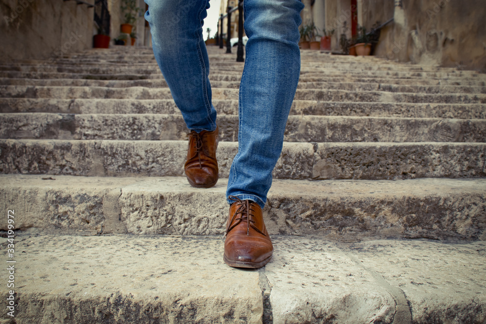 One men in brown shoes walking down outdoor stairway in city, detail of his legs One men in brown shoes walking down outdoor stairway in city, detail of his legs