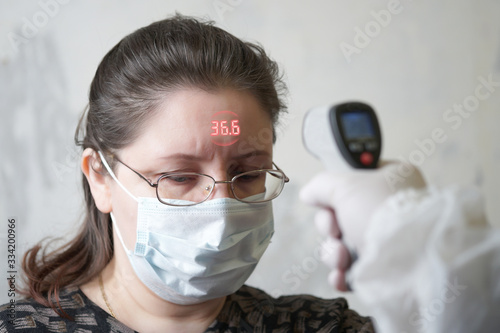 the doctor measures the temperature on the forehead with a thermometer