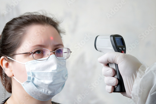 the doctor measures the temperature on the forehead with a thermometer