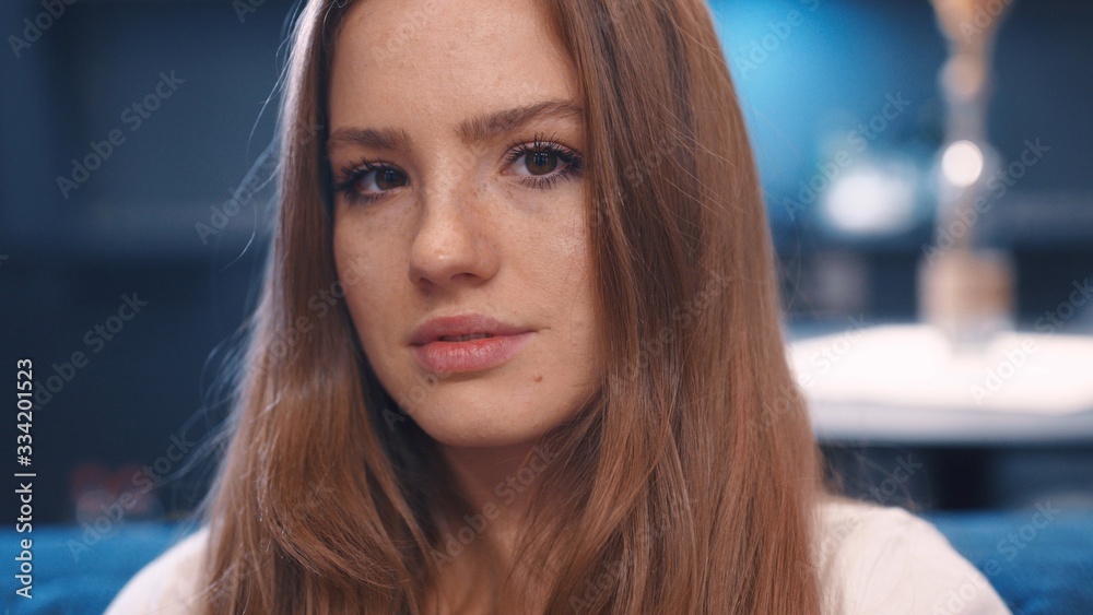 Close up portrait of young dreaming pretty red hair woman in white t-shirt with freckles open eyes and looks to camera in modern apartment feeling happy great evening good emitions home comfortable Close up portrait of young dreaming pretty red hair woman in white t-shirt with freckles open eyes and looks to camera in modern apartment feeling happy great evening good emitions home comfortable