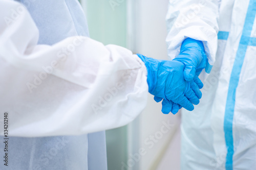doctor and nurse in personal protective equipments or PPE shaking hands. medical, covid-19, coronavirus concept