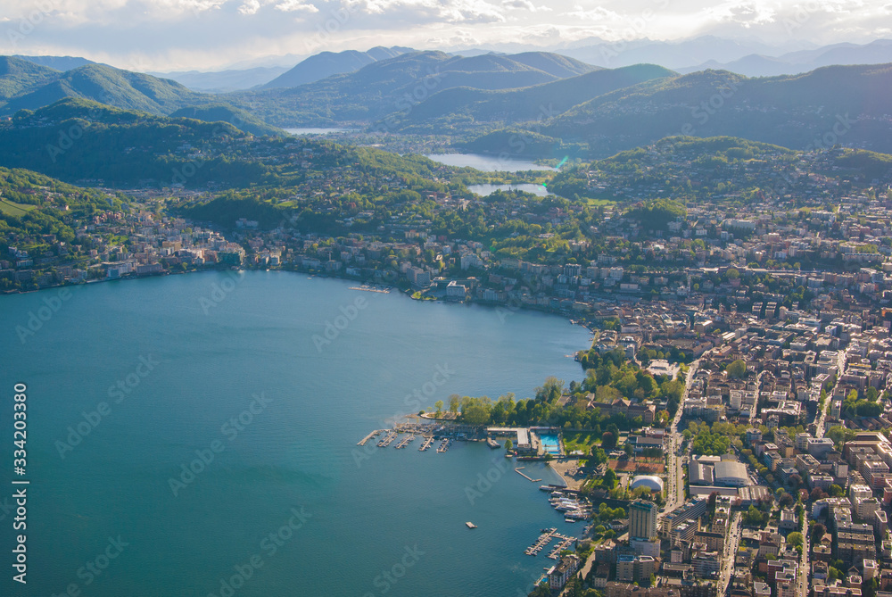 Top view of the city of Lugano, Switzerland from the height of Mount Monte Bre. Beautiful mountain scenery on a sunny summer day. View of Lake Lugano and the Alpine mountains.