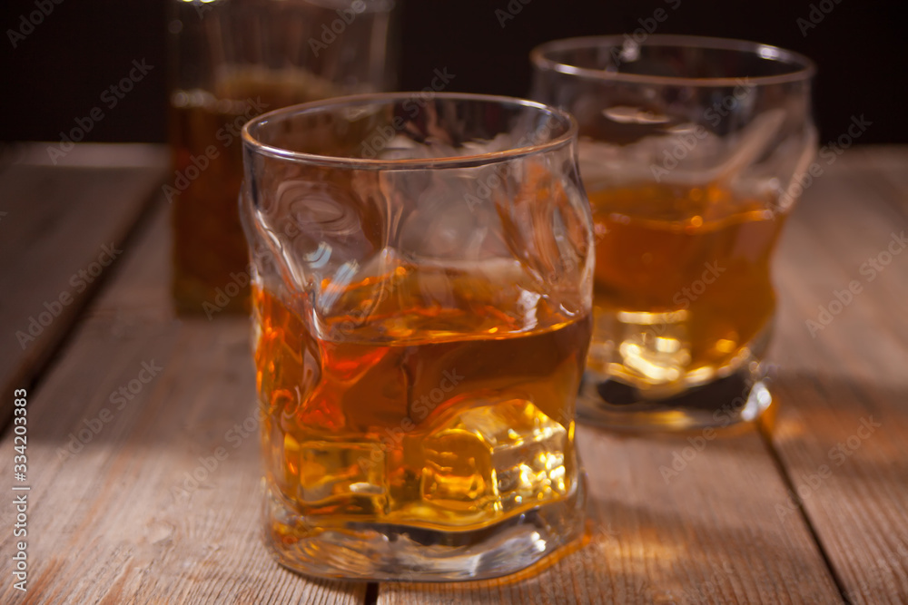 Two glasses of whiskey on the wooden table.