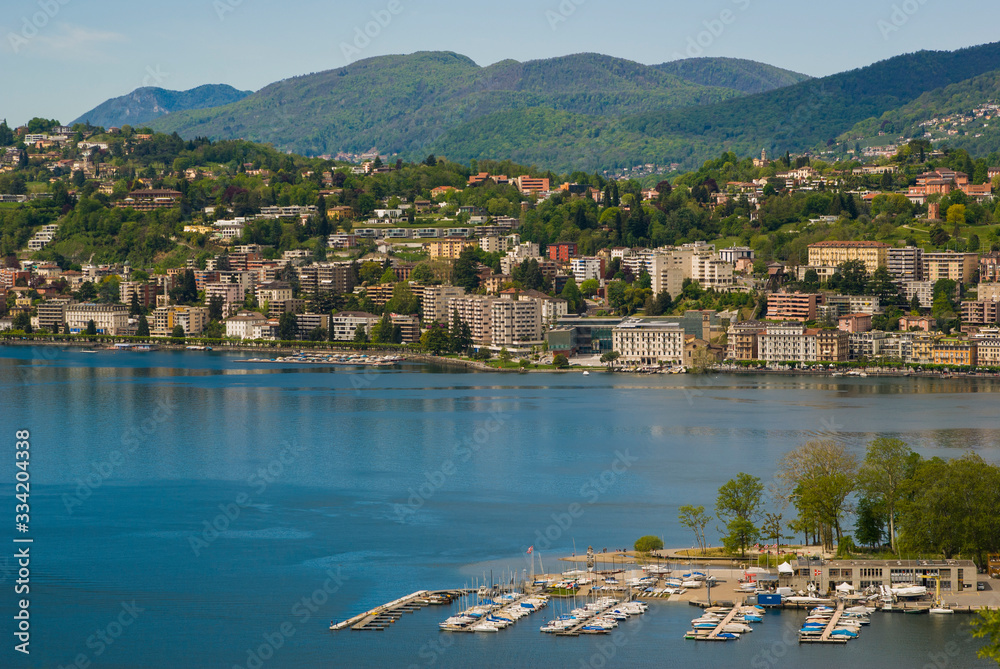 View of the lake and the city of Lugano on a sunny summer day. Mountain landscape in the city of Lugano, Switzerland. 