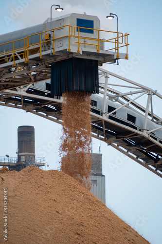 Wood chips coming out of shoot at paper mill.