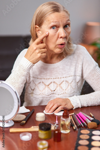 Woman examines wrinkles around her eyes.
