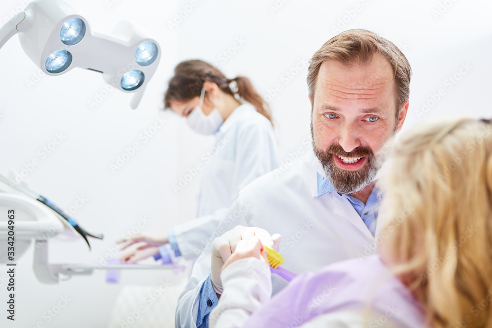 Dentist explains child to brush right teeth Dentist explains child to brush right teeth