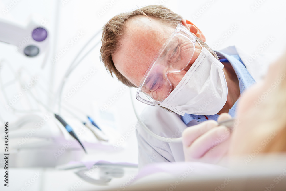 Naklejka premium Dentist with drill in the treatment of patient