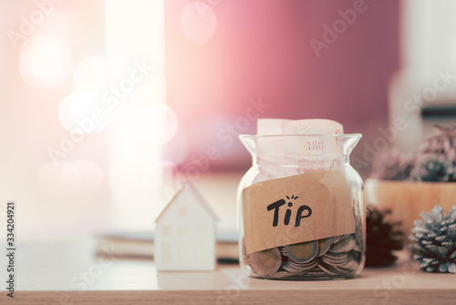 Glass jar with tip box tag and money coins inside photo
