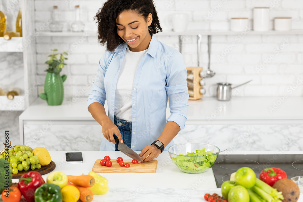 Beautiful young afro woman preparing vegetable salad at home Beautiful young afro woman preparing vegetable salad at home
