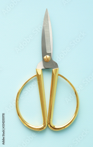 Household scissors metal blades and gold handles on a blue background. Selective focus