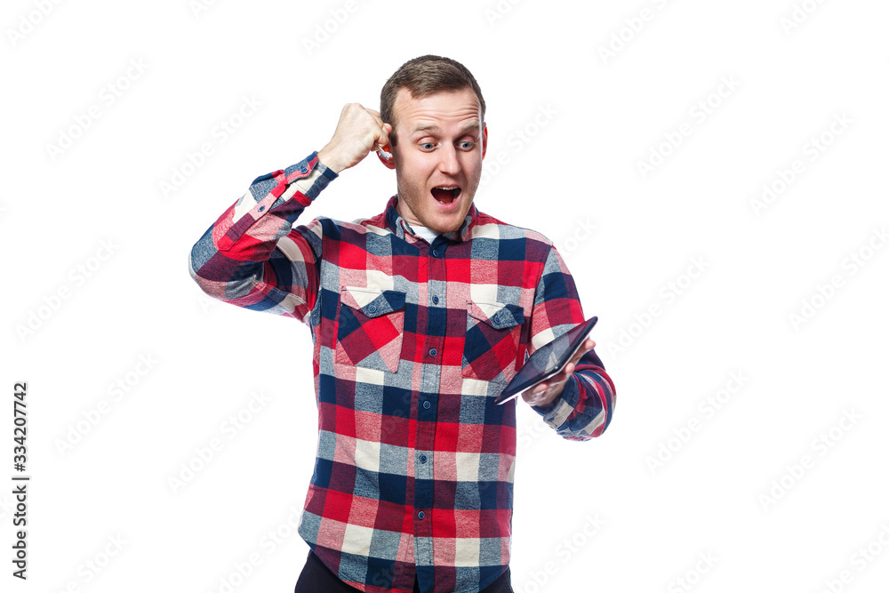 white-skinned male freelancer, repairman, scratches the protective film on the tablet screen and removes it. wearing a shirt. Emotional portrait. Isolated on white background white-skinned male freelancer, repairman, scratches the protective film on the tablet screen and removes it. wearing a shirt. Emotional portrait. Isolated on white background