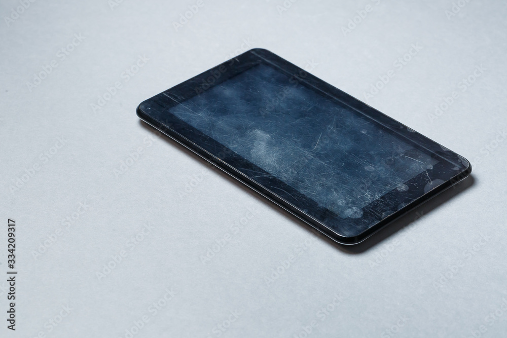 Black scratched tablet with a protective film on a gray background. Protect your device screen Black scratched tablet with a protective film on a gray background. Protect your device screen